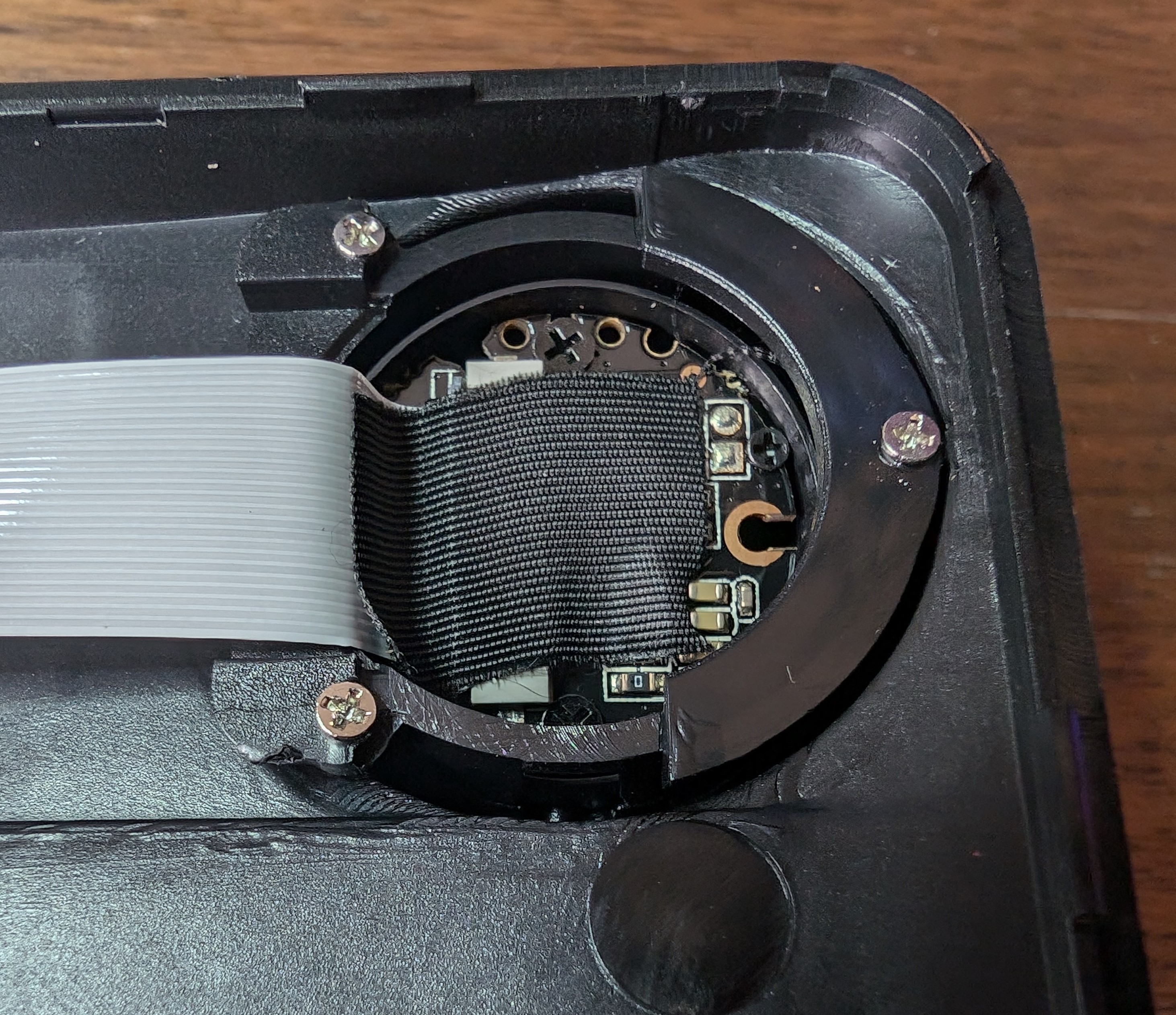 The forward facing camera is in a swivel mount and is highly integrated; there's nothing under that black tape.