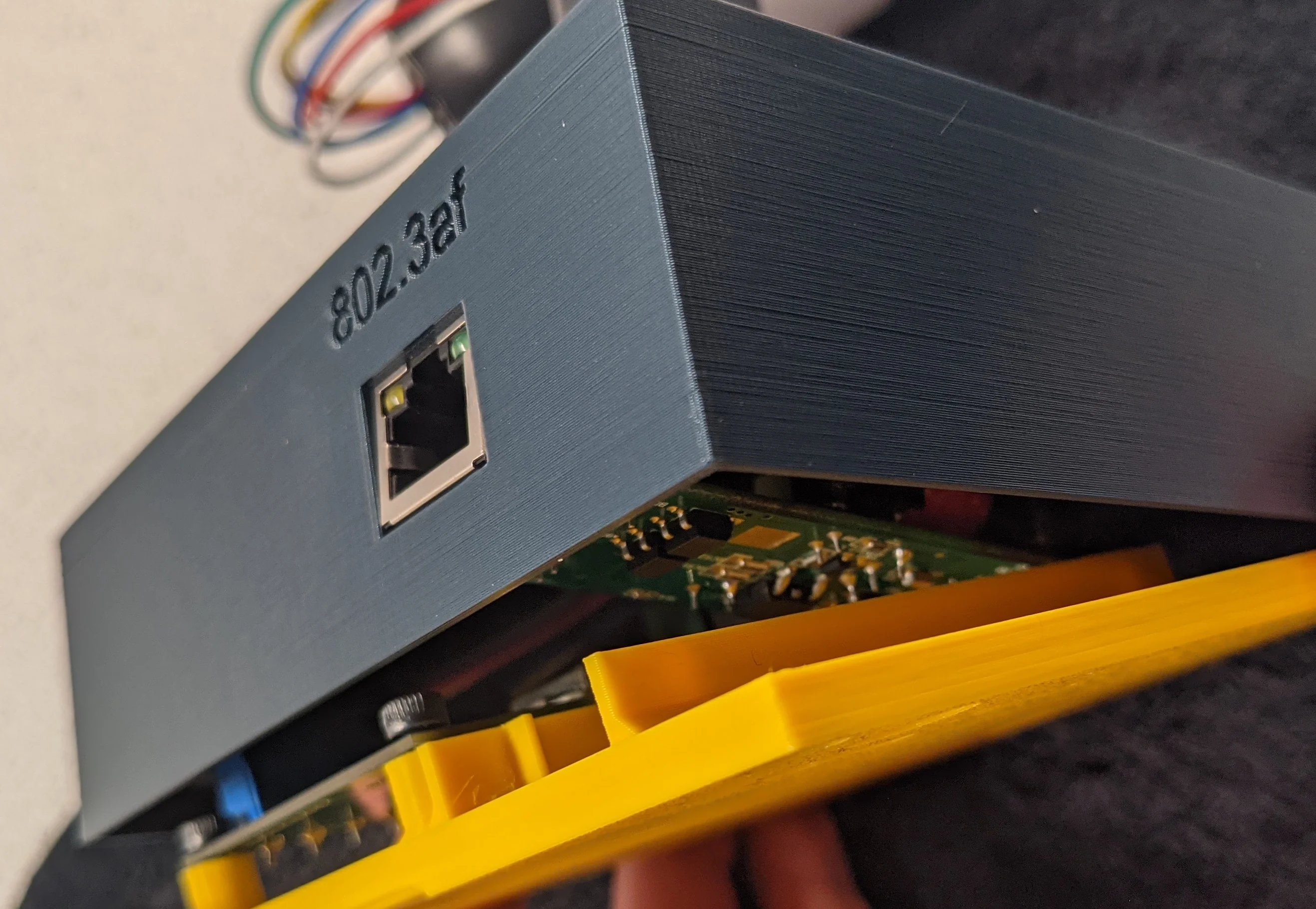 Picture showing assembly detail; the base plate acts like a lever to carefully line the PoE jack up with the enclosure body.