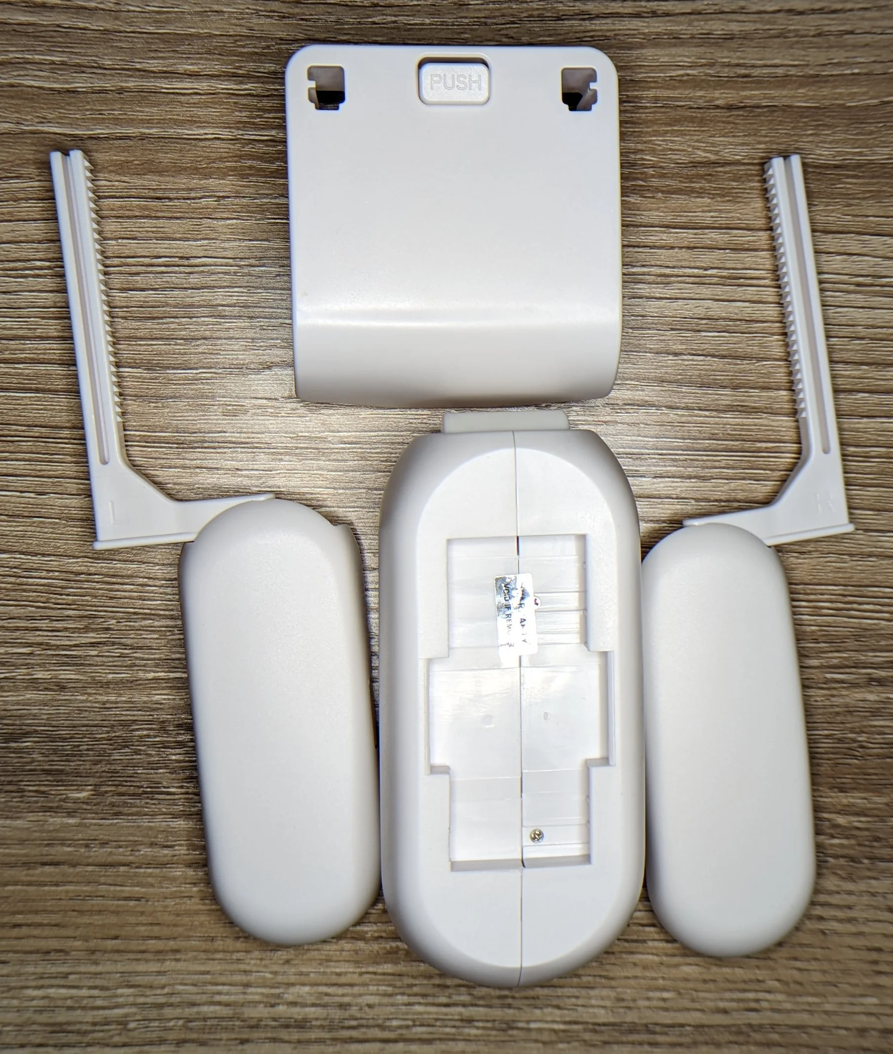 Closeup photo of a curtain robot with the modular curtain rod interface hardware detached next to the curtain robot which has also been turned on its side. The machine screws holding the unit together are visible.