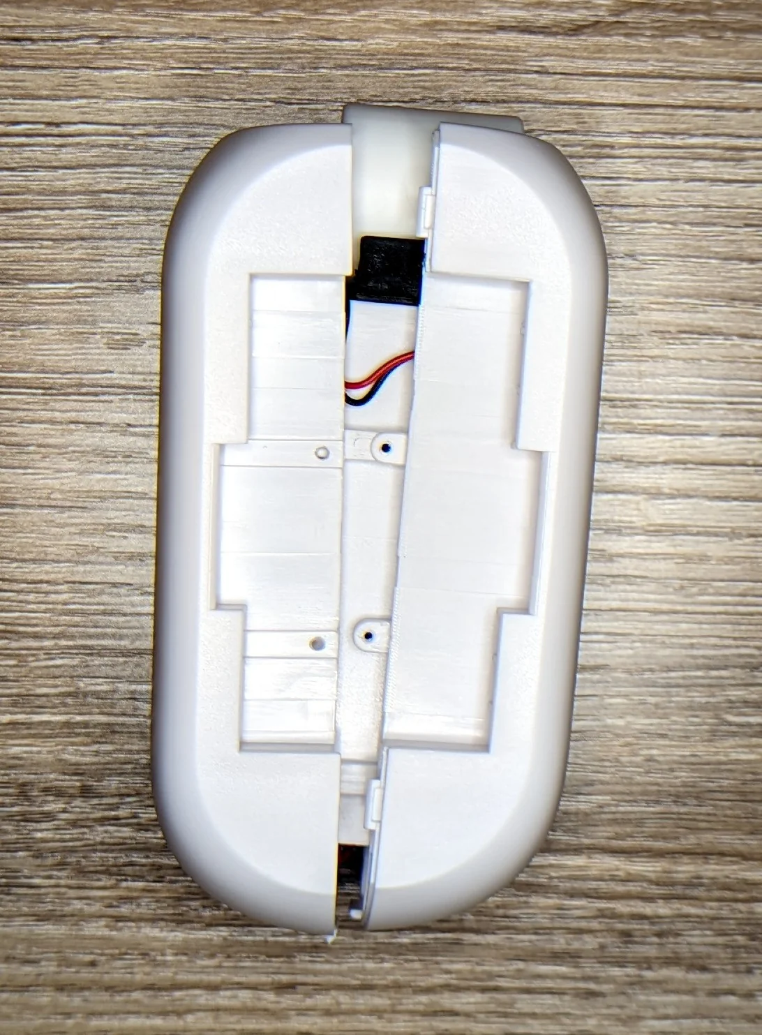 Photo showing a curtain robot that has been cracked open along it's main seem. A small glimpse at a few wires and internal components.