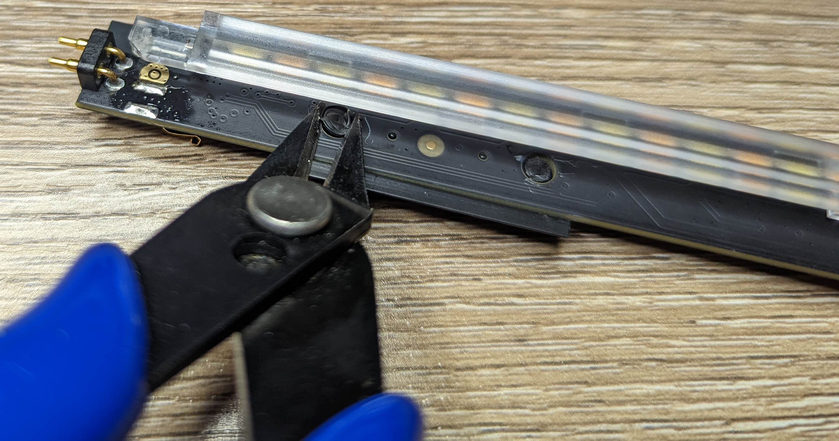 Photo showing flush cutting snips used to remove a component that has been heat staked onto the main PCB