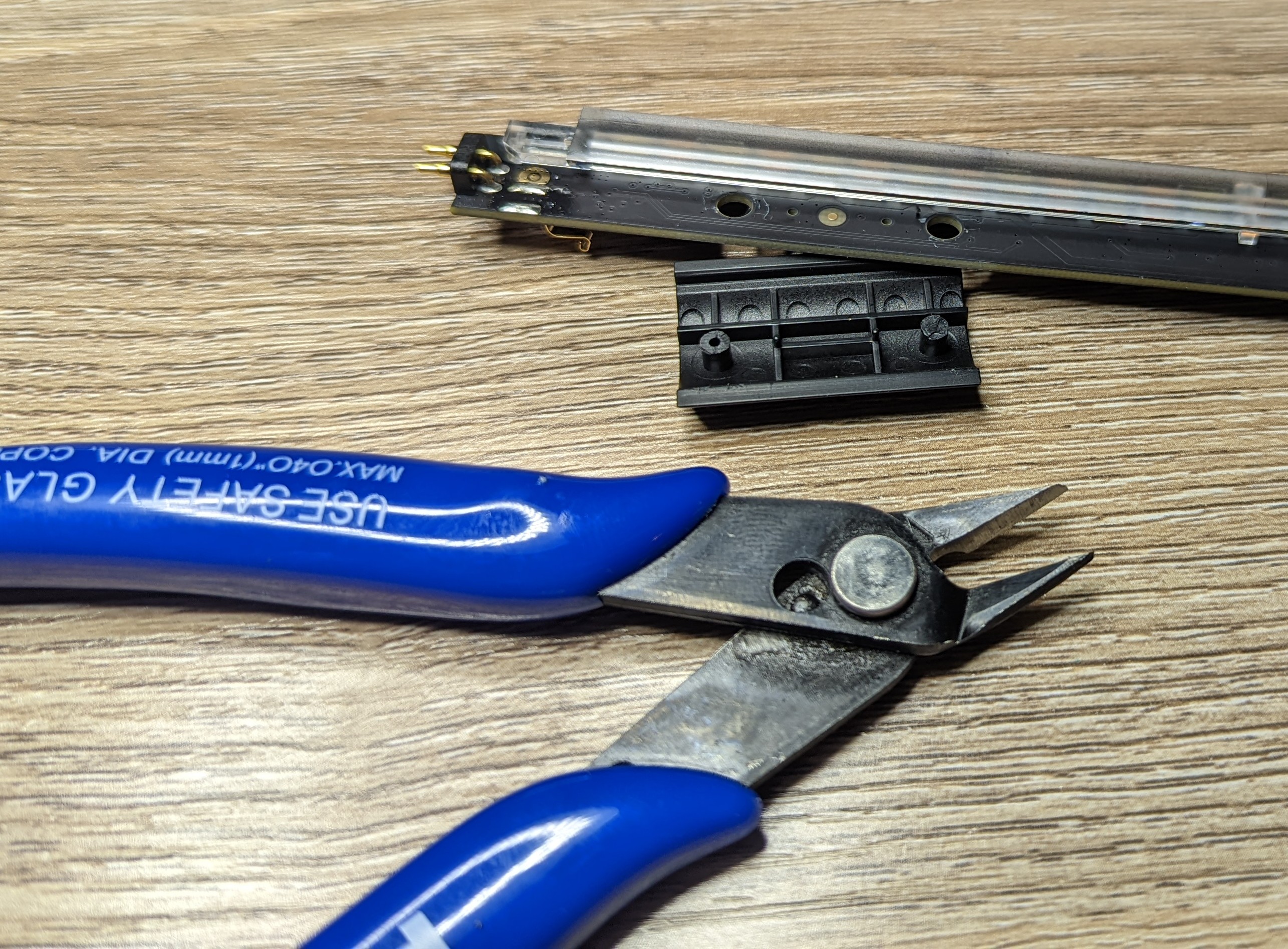 Photo showing flush cutting snips and the removed component next to the PCB